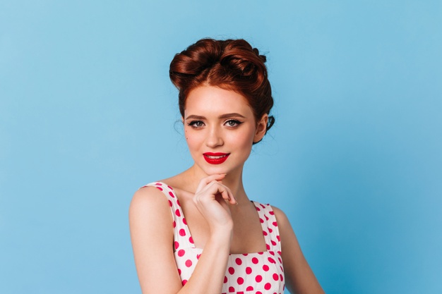 curious-woman-white-polka-dot-dress-looking-camera-charming-pinup-ginger-girl-standing-blue-space_197531-15152